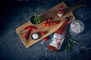 peat smoked tomato bottle lying on a counter between other Bloody Mary ingredients