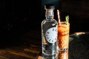 Bottle of Broken Clock Vodka next to a Bloody Mary cocktail made with peat smoked tomato juice