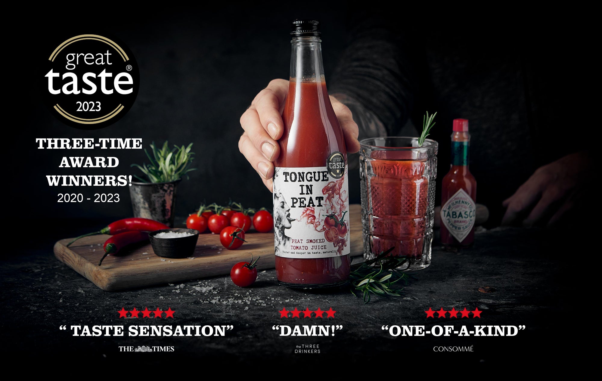 A banner of a person showing off a bottle of Tongue in Peat smoked tomato juice with cherry tomatoes and chilli and tabasco around it with stickers and reviews