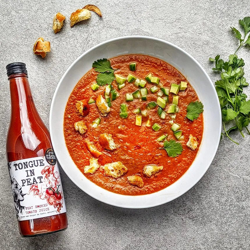 bottle of tongue in peat smoked tomato juice next to a bowl of gazpacho soup