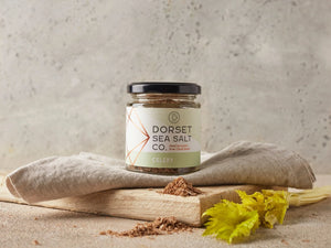 a jar of dorset celery sea salt on top of a cloth laid on a wooden board